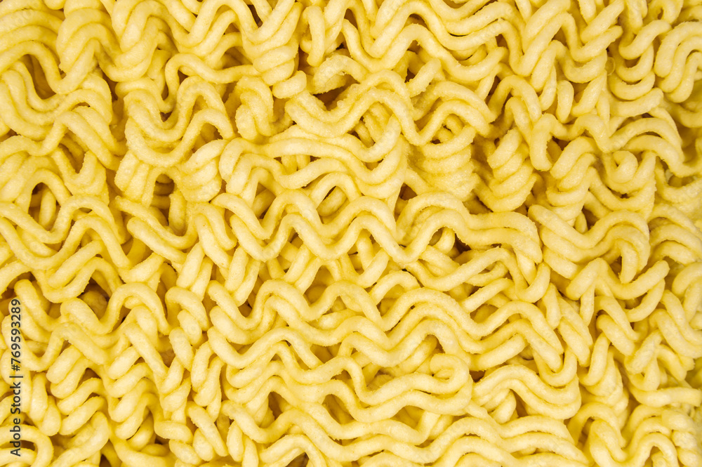 Obraz premium A close up of yellow ramen noodles. The noodles are long and thin, and they are arranged in a way that makes them look like they are curled up. The image has a warm and inviting mood