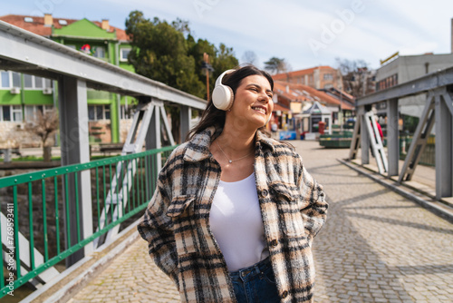 One young girl or woman is listening to music on her wireless headphones and enjoying the sun outdoors 