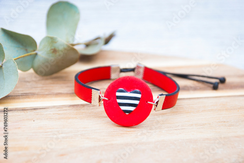 Red bracelet with striped hearton leather cord.