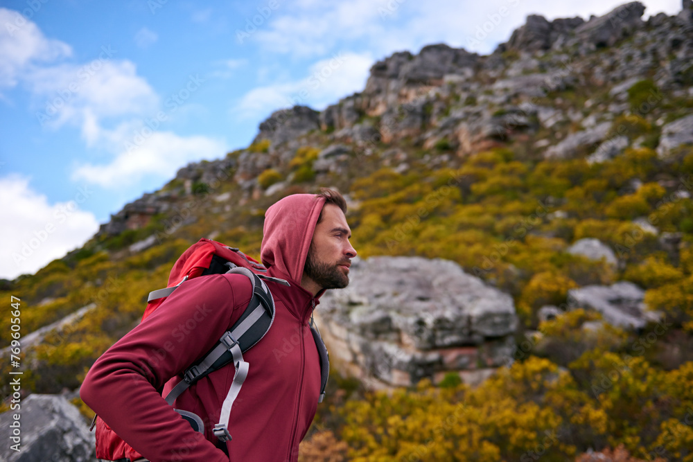 Man, hiking and workout in outdoor nature, mountain and peace or calm on rocks for wellness. Male person, exercise and travel with backpack on vacation, adventure and explore for fitness or trekking
