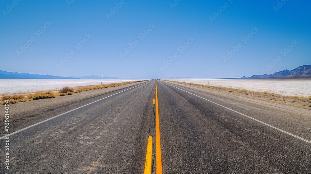 A long, empty road with a clear blue sky above