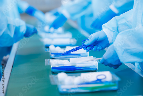 Surgery kit on conveyor line, closeup of medical staff gloved hands sorting blue med instrument scissors, tool of doctor pharmacy, clear light toning photo