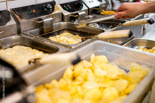Freshly fried potato chips sizzle in a commercial kitchen, capturing the enticing moment of snack preparation