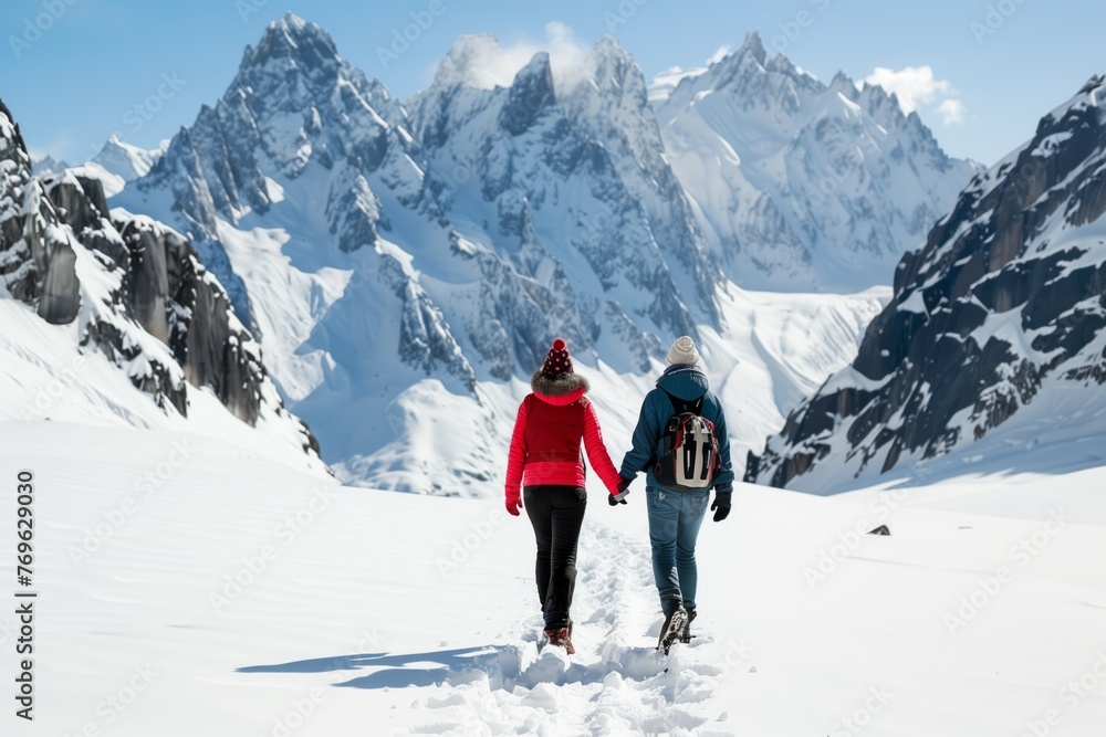 couple holding hands, walking on snow towards peaks