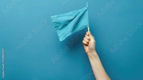 A hand holding a small light blue flag against background.