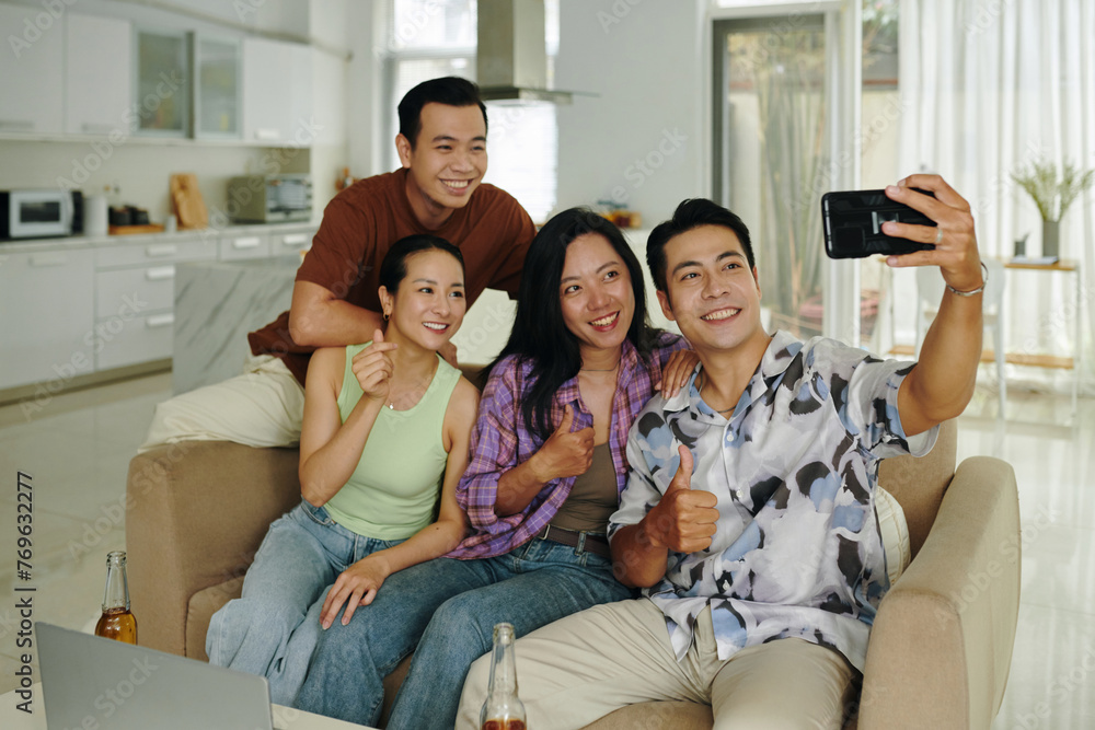 Happy Vietnamese man taking selfie with friends at home