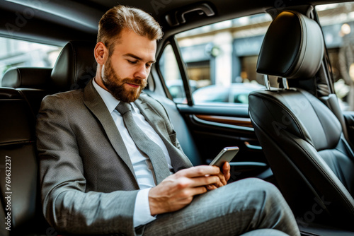Focused businessman in a suit using a smartphone in a luxury car © Tixel