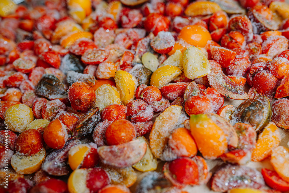 Heap of halved, frosty tomatoes with ice crystals, in a mix of red and yellow colors. Heap of halved, frosty tomatoes with ice crystals, in a mix of red and yellow colors.
