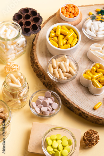 Various vitamins and minerals, food supplements in small jars on a wooden desk, top view. Vitamins and dietary supplements to improve immune system and health. Healthy lifestyle. Vitamin D3, C, A, E.