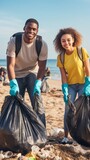 A man and woman are standing on a beach, holding plastic bags of trash