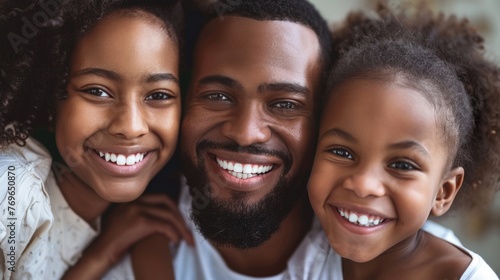 A joyful family moment with a man and two young girls all smiling and embracing showcasing a warm and loving bond.