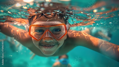 A joyful child underwater wearing orange goggles smiling broadly and surrounded by bubbles in a swimming pool. © iuricazac