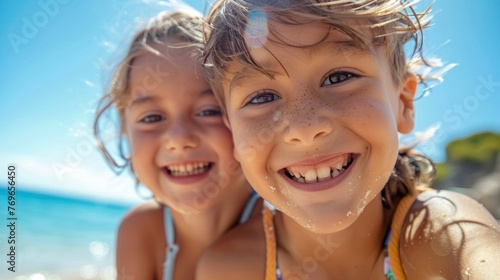 Two young girls with sandy faces smiling at the camera enjoying a day at the beach.