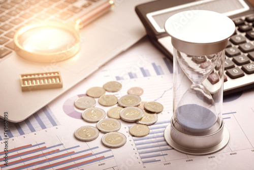 Coins, hourglasses, and other office supplies placed on financial data charts