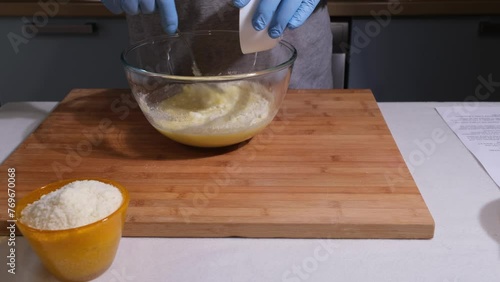 Mani dell'uomo versano nella ciotola con i liquidi il formaggio grattugiato per preparare la torta al formaggio photo