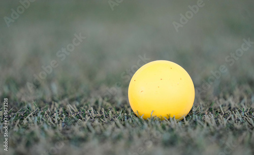 Yellow lacrosse ball sitting on the turf