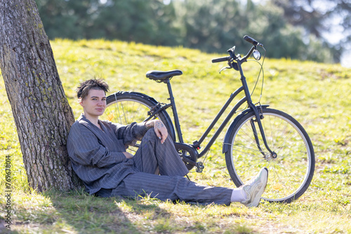 A woman is sitting on the grass next to a bicycle