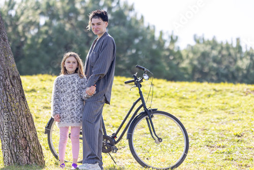 A woman and her daughter little girl are standing next to a bicycle