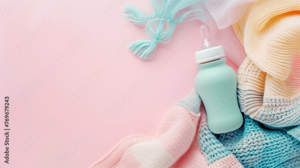 Baby essentials with knitted clothes, a bottle, and accessories on pink background. - obrazy, fototapety, plakaty 