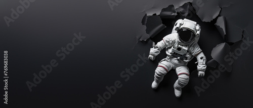 An astronaut hovers in black space, artfully framed by a jagged tear, illustrating isolation and space oddity