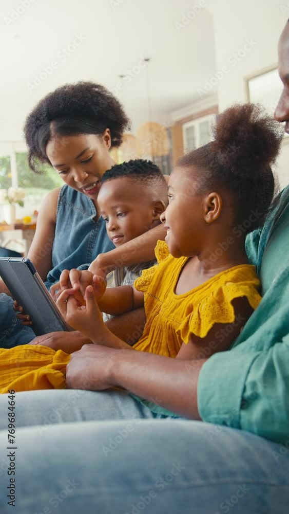 Vertical video of family indoors at home sitting on sofa with digital tablet playing game with grandparents in background - shot in slow motion Vertical video of family indoors at home sitting on sofa with digital tablet playing game with grandparents in background - shot in slow motion