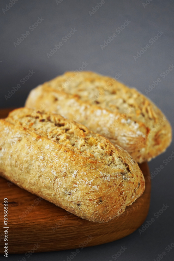 Two loaves of bread on a wooden board on a gray background