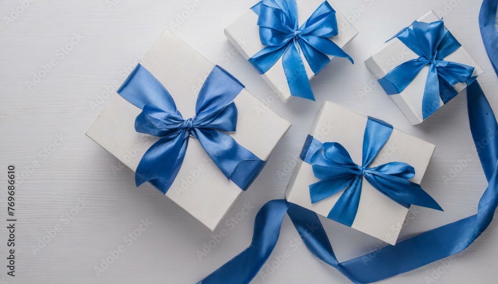 Top view of blue and white giftboxes with blue satin ribbon bow isolated on white background with empty space Top view of blue and white giftboxes with blue satin ribbon bow isolated on white background with empty space