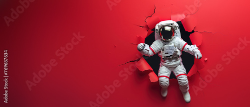 A striking visualization of an astronaut powerfully breaking through a vibrant red paper background
