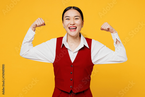 Side view young fun corporate lawyer employee business woman of Asian ethnicity wear formal red vest shirt work at office show muscles biceps isolated on plain yellow background studio Career concept
