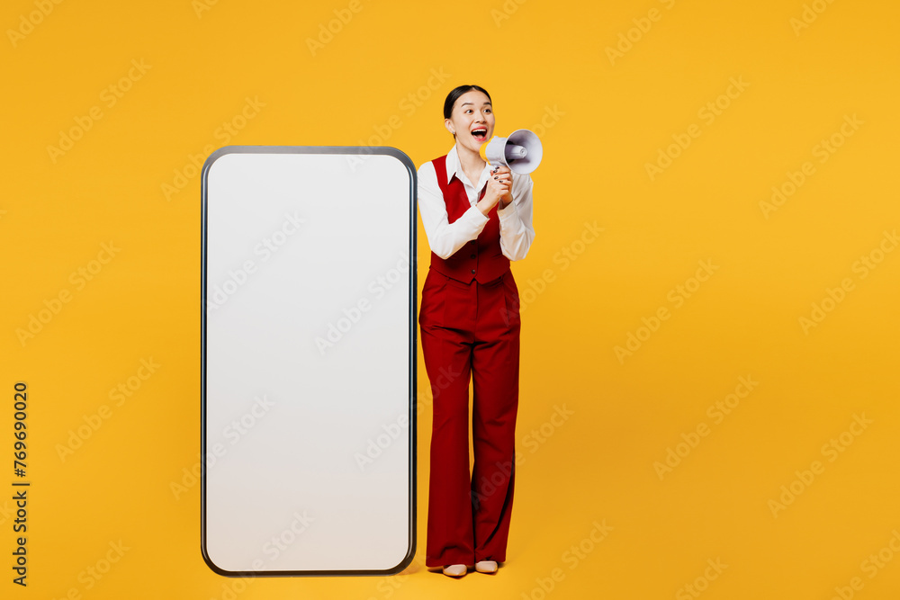 Φωτογραφία Full body young lawyer employee business woman of Asian ethnicity wear formal red vest shirt work at office big blank screen mobile cell phone scream in megaphone isolated on plain yellow background