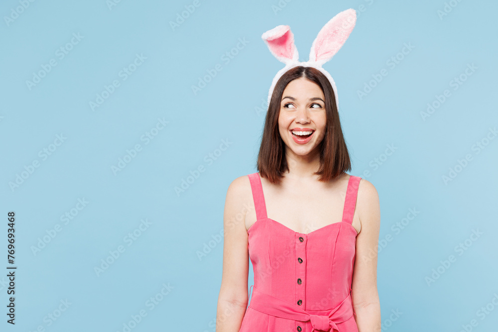 Young surprised shocked fun woman she wear pink casual clothes rabbit look aside on area bunny ears isolated on plain pastel light blue cyan background studio portrait. Lifestyle Happy Easter concept. Young surprised shocked fun woman she wear pink casual clothes rabbit look aside on area bunny ears isolated on plain pastel light blue cyan background studio portrait. Lifestyle Happy Easter concept.