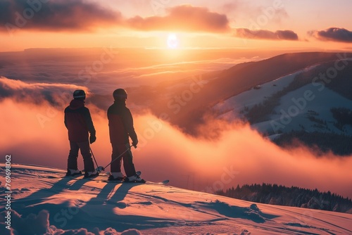 Two skiers on a high ridge gaze into a sea of clouds under a soft sunrise, the sky ablaze with warm hues reflecting off the snowy expanse.