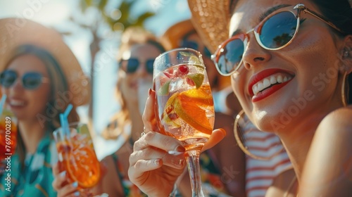 Group of friends drinking cocktails at party on luxury resort. Summer vacation concept. photo