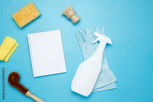 Various accessories cleaning products, sprays, rags, sponges and brushes. Mock up white notebook. Top view, flat lay, copy space