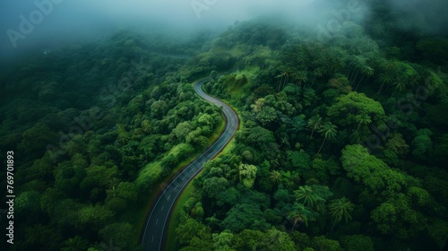 Aerial top view beautiful curve road on green forest in the rain season.