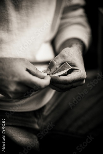 Grayscale shot of an adult man folding a piece of paper