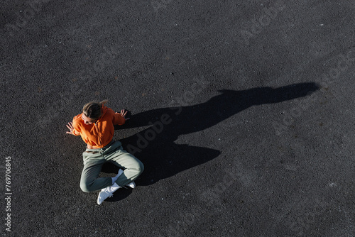 Top view of a young adult woman wearing activewear, sitting on the asphalt