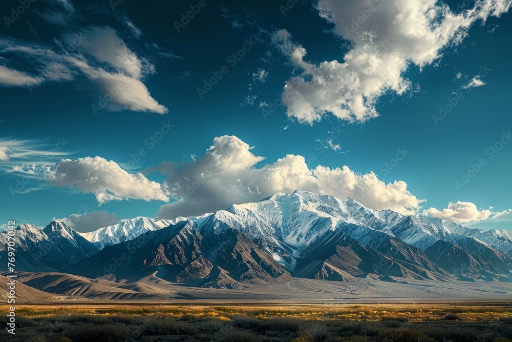 A wide-angle shot capturing a majestic mountain range with peaks and valleys under a cloudy sky