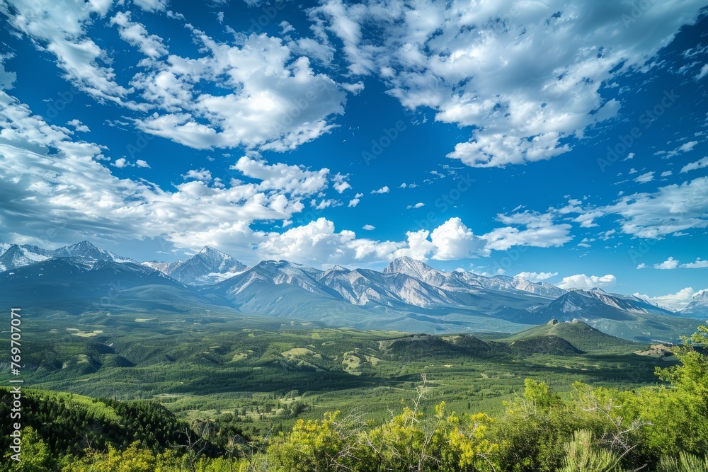 A wide-angle view of a majestic mountain range, showcasing peaks and valleys under cloudy skies
