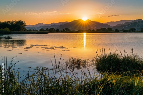 The sun is setting over a lake  casting a warm glow on the water  with majestic mountains in the background