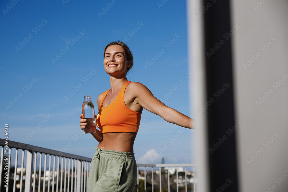 Young woman takes a refreshing drink of water after a workout session