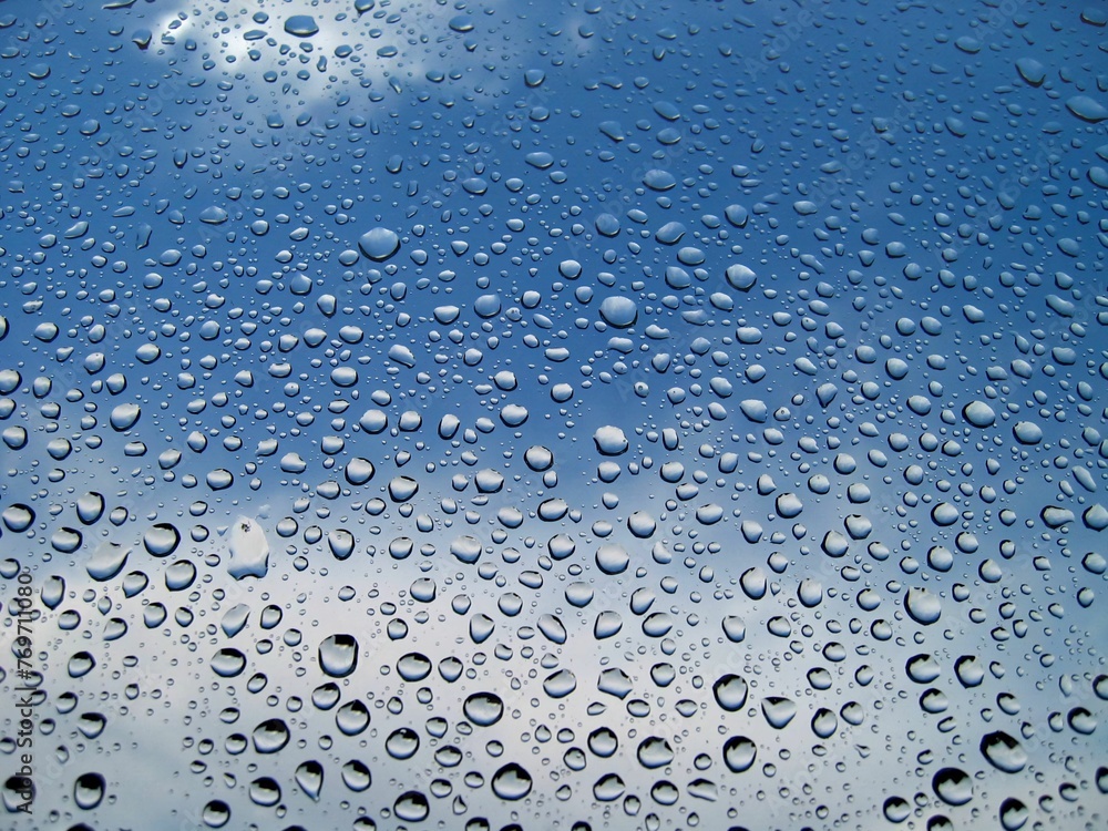 Closeup of a glass window with waterdrop against blue sky Closeup of a glass window with waterdrop against blue sky