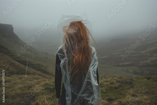 Girl wrapped in plastic. Barefoot long hair young woman with its body tangled in a plastic bag against green valley. Environmental protection concept. Ecology, future and nature pollution global issue