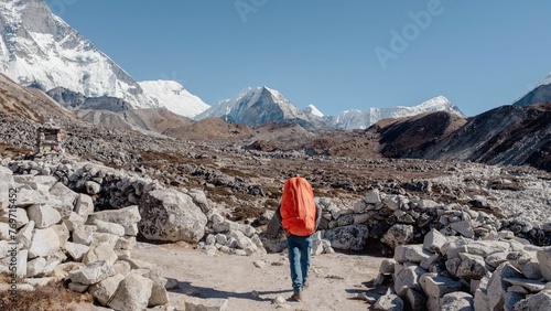 Man is walking up a mountain path while carrying multiple stones.