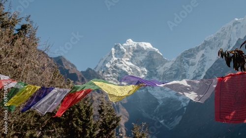 Range of colorful flags blowing in the wind against a mountain backdrop.