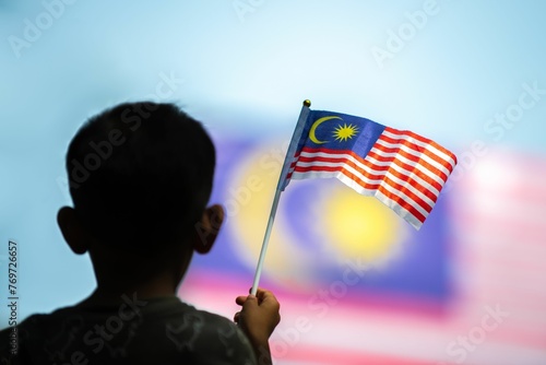 a boy holds a malaysia flag as an malaysian and malaysian flags are seen in the photo