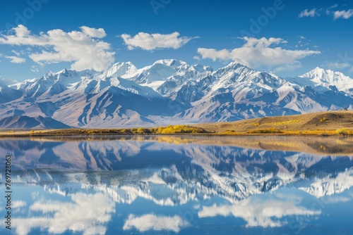 Snowcapped mountain range reflected in still lake water on a clear day