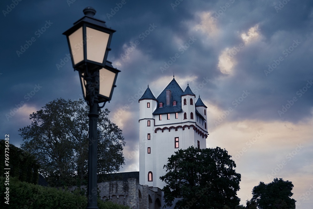 Low angle shot of a castle tower near a vintage street lamp under a gloomy sky in Eltville, Germany - obrazy, fototapety, plakaty 