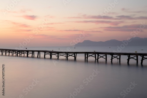 a dock extending into the water as it's sunset © Wirestock