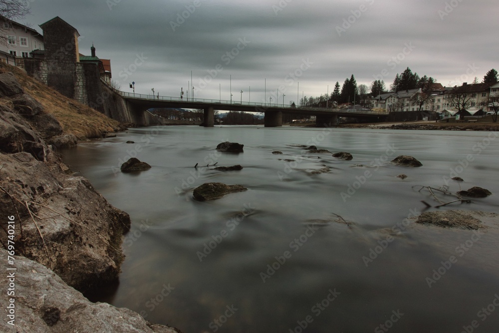 Cloudy, dark sky over a river with a bridge, creating a somber atmosphere